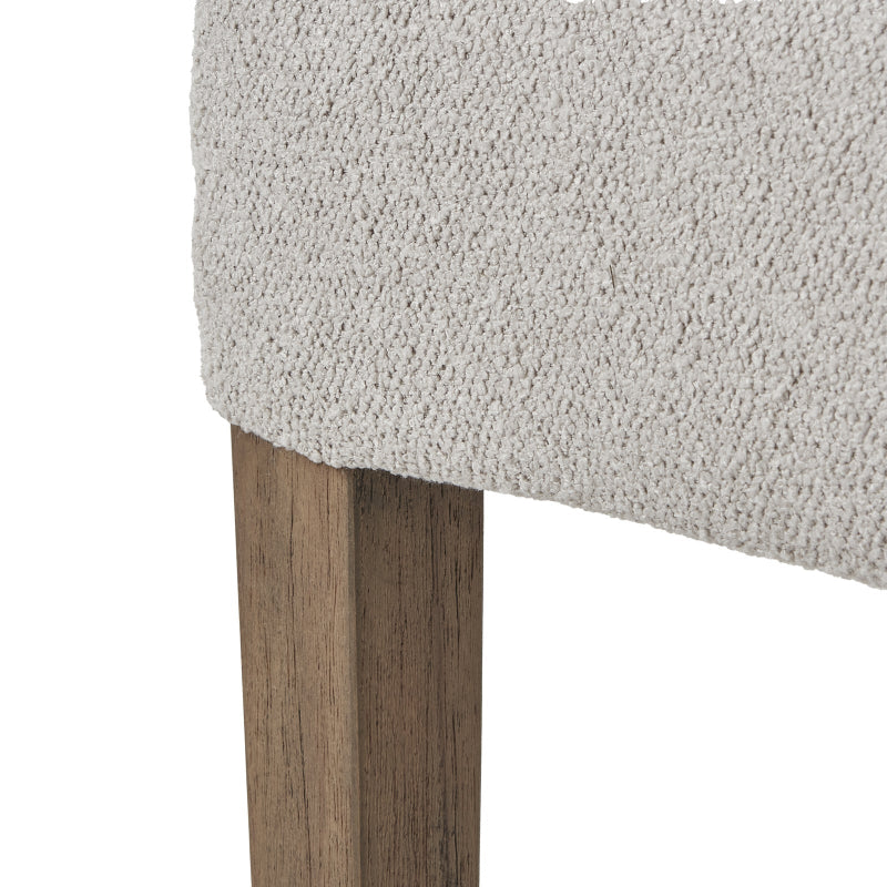 Close-up of a textured neutral cushioned chair with wooden legs on a white background