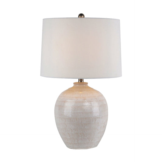 Table lamp with textured white base and white shade on a white background