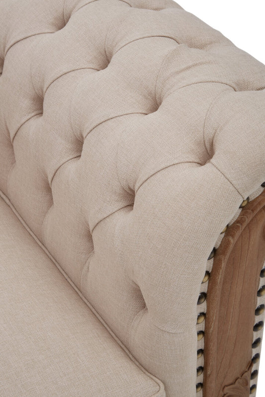 Close-up of a tufted beige upholstered headboard with brown trim.