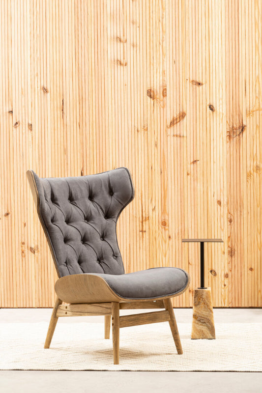 Gray upholstered chair with wooden frame against a wooden paneled wall.