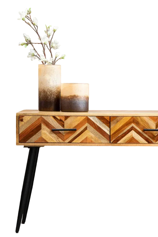 Wooden console table with chevron pattern and two decorative items on a plain background