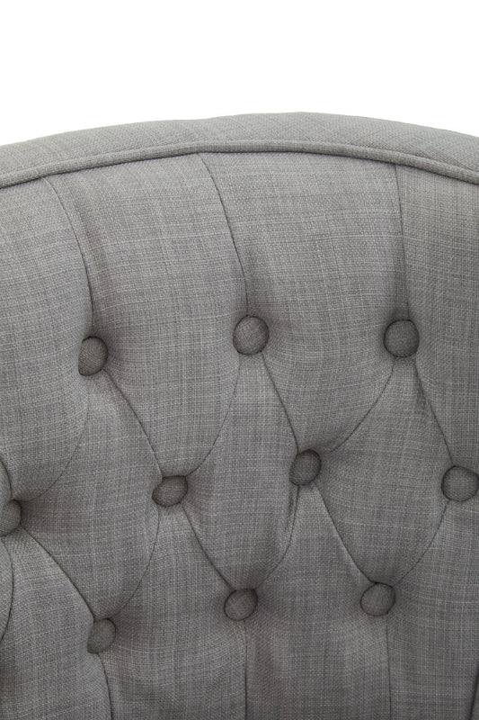 Close-up of a gray upholstered headboard with tufted design