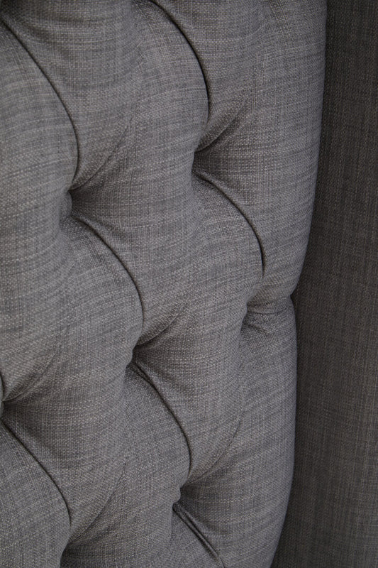 Close-up of a gray upholstered chair with tufted design