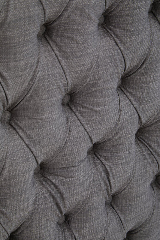 Close-up of a tufted gray fabric headboard