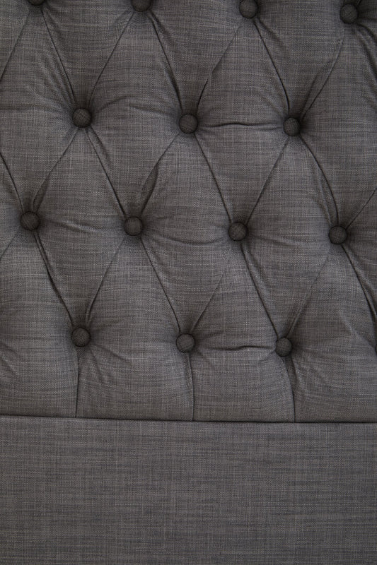 Close-up of a tufted gray upholstered headboard