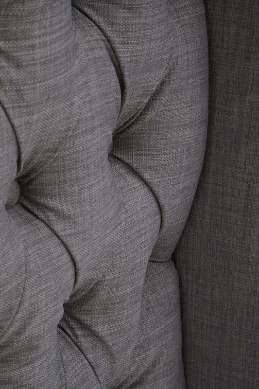 Close up of grey fabric headboard showing deep button tuff