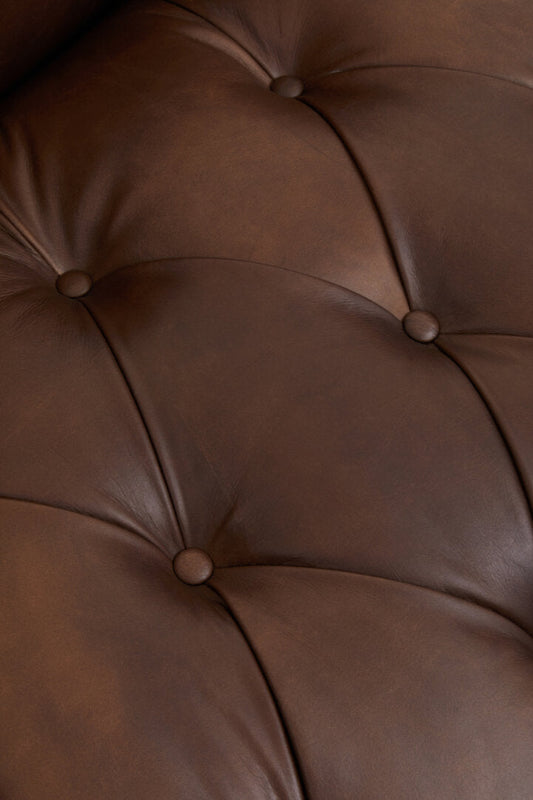 Close-up of a brown leather surface with tufted design