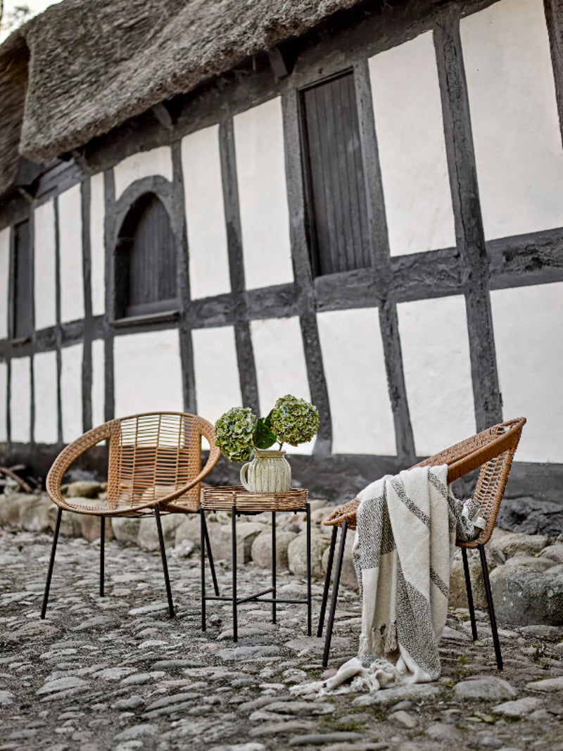 Wicker chairs and a small table with a plant in front of a half-timbered building.