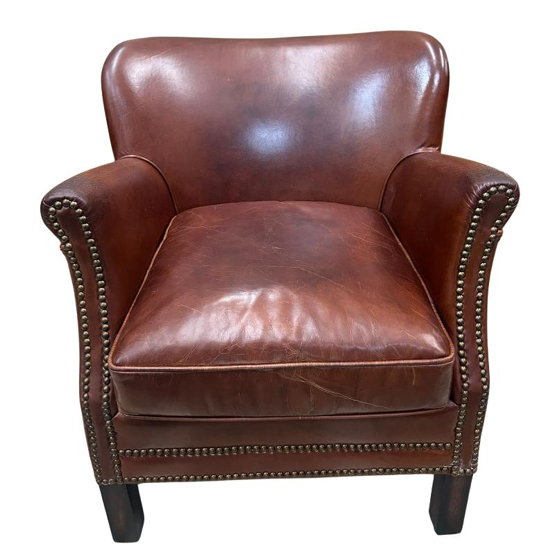 A classic brown leather armchair with rolled arms, nailhead trim, and dark wooden legs, shown against a plain white background.