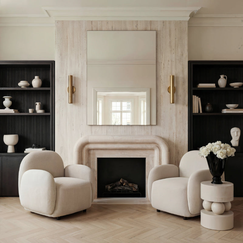 Modern living room with white armchairs, a fireplace, and decorative elements.