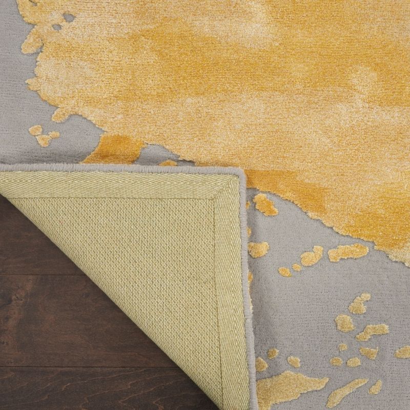 Close-up of a textured rug with yellow and gray pattern on a wooden floor.