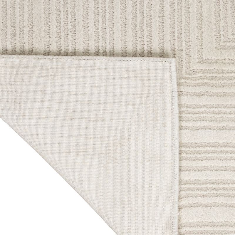 Close-up of a light beige textured rug corner showing a striped pattern and a white underside backing.