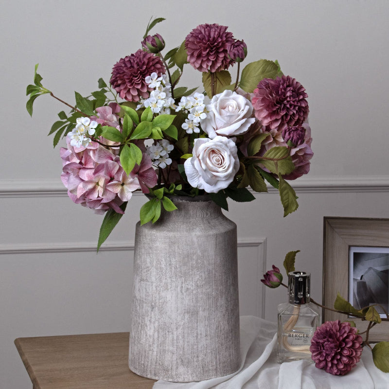 Floral arrangement in a textured vase on a table with a neutral background