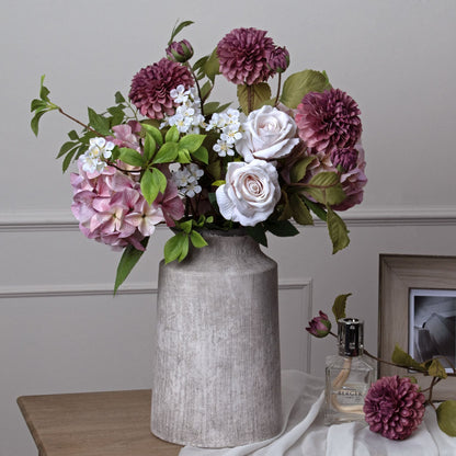 Floral arrangement in a textured vase on a table with a neutral background