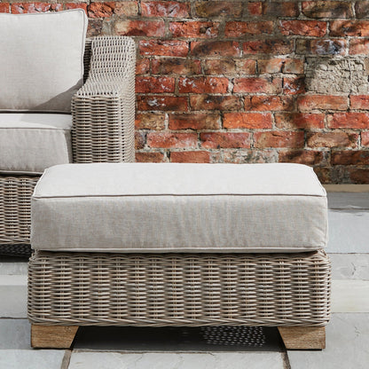 Wicker ottoman with cushion against a brick wall