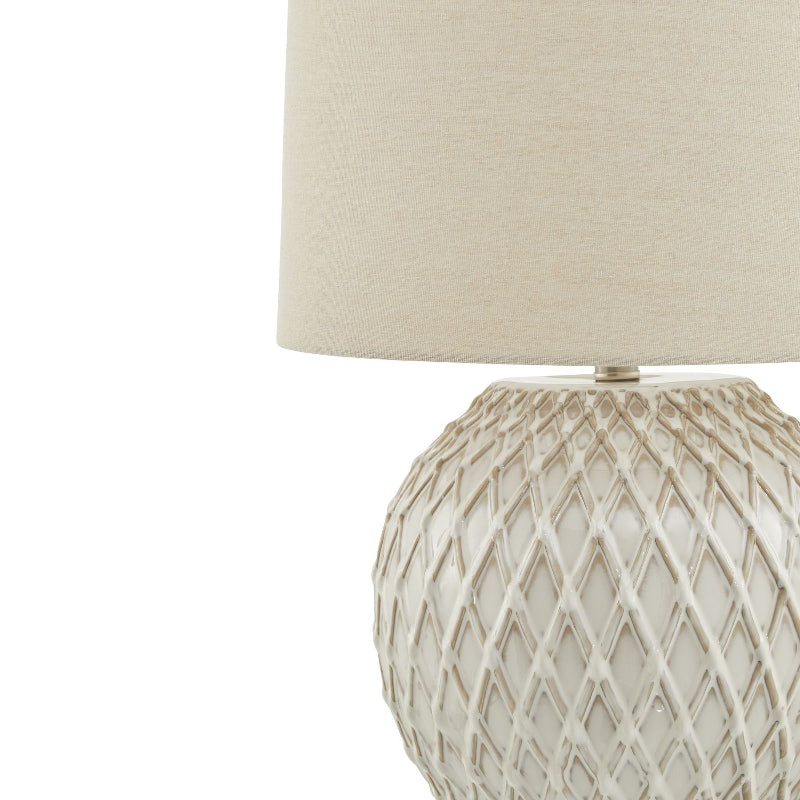 Decorative lamp with textured base and cream shade on a white background