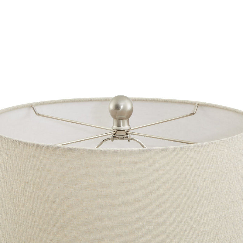 Close-up of a cream lampshade with a metallic finial on a white background