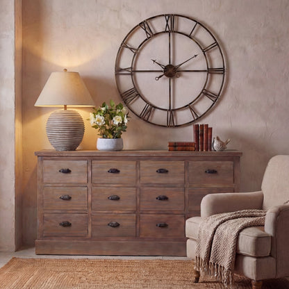 Wooden dresser with large wall clock, lamp, and books in a room setting.