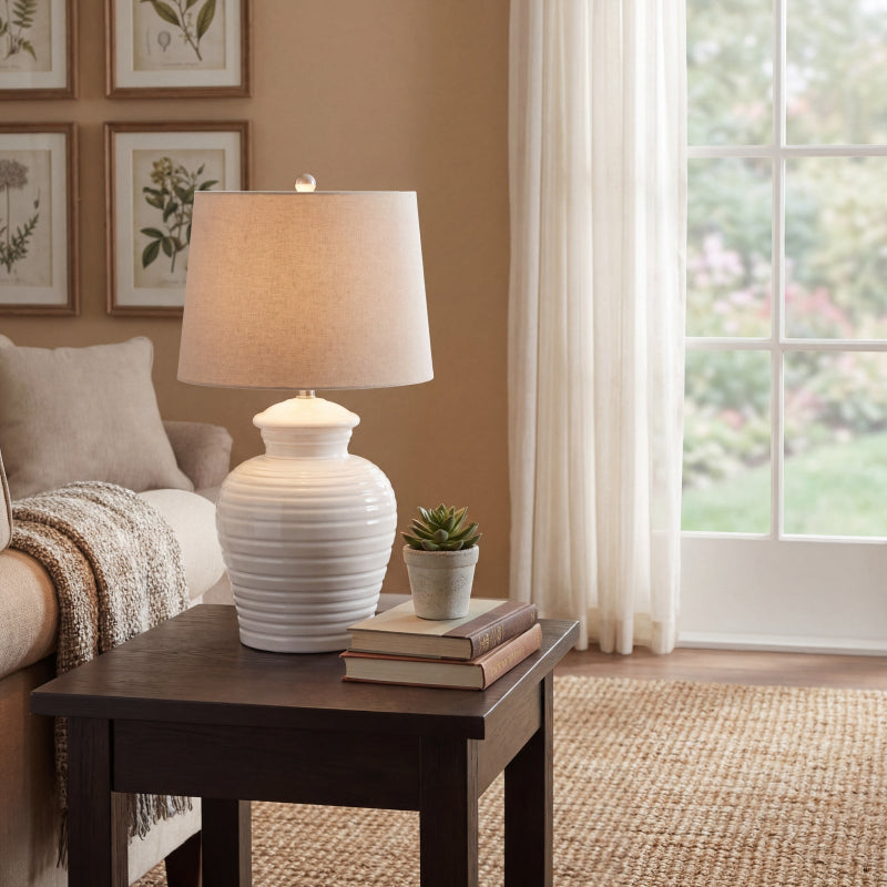 White lamp on a wooden side table in a living room with a couch and decor.