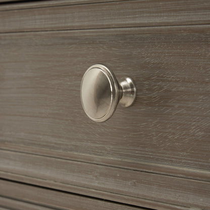 Metallic cabinet knob on a wooden drawer