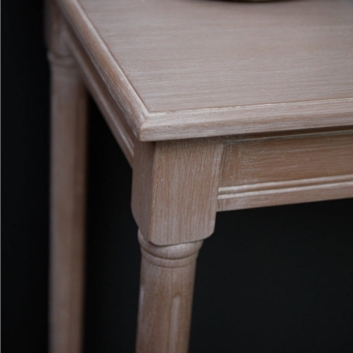 Wooden side table with a decorative item on top against a black background