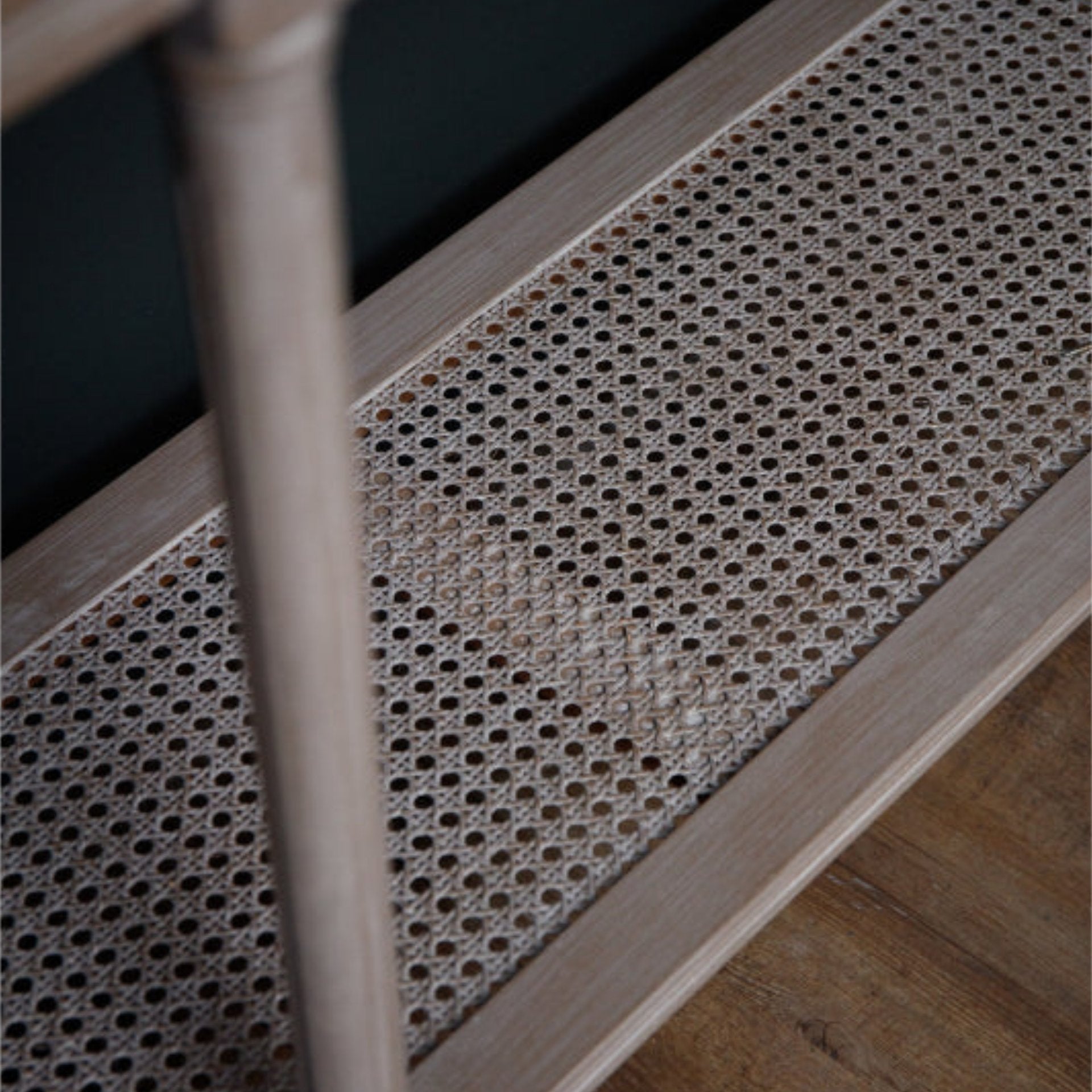 Rattan shelf with wooden legs on a dark background
