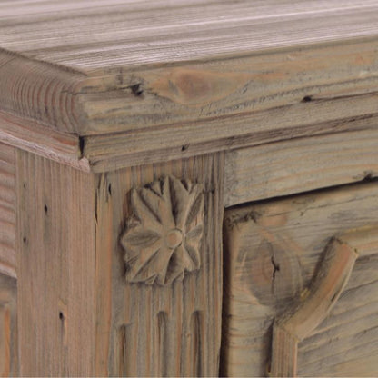 Close-up of a rustic wooden cabinet corner with a carved floral knob, weathered light brown finish, and visible wood grain.