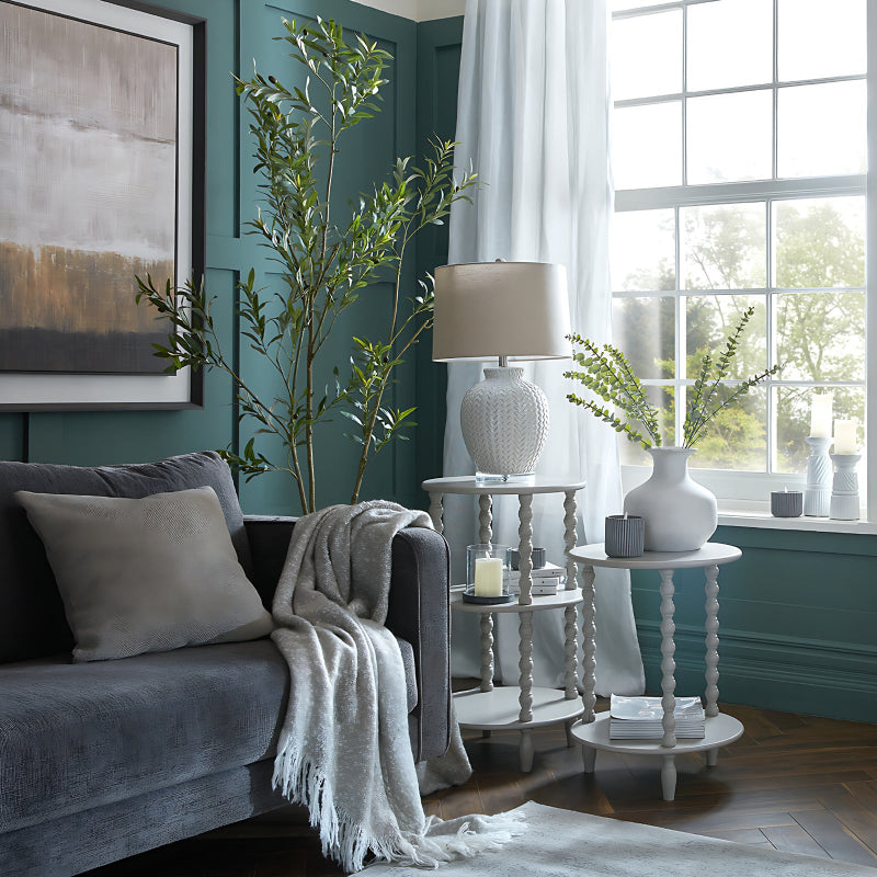 Living room with gray sofa, decorative plants, and side tables.