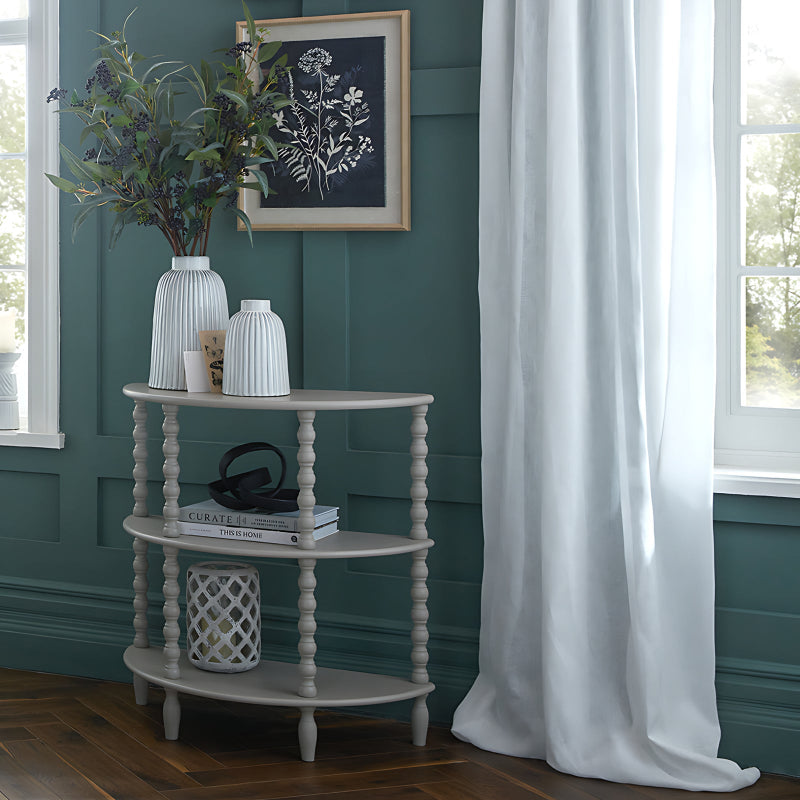 Three-tiered wooden side table with decorative items against a teal wall.