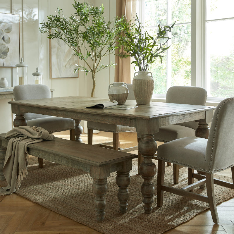 Dining room with wooden table, chairs, and a bench in a bright room.