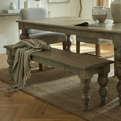 Wooden dining table with bench and chair in a room with light-colored walls and wooden flooring.