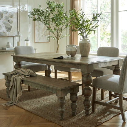 Dining room with wooden table, chairs, and a bench on a rug.