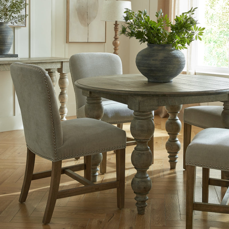 Dining room with wooden table and chairs, featuring a vase with greenery on the table.