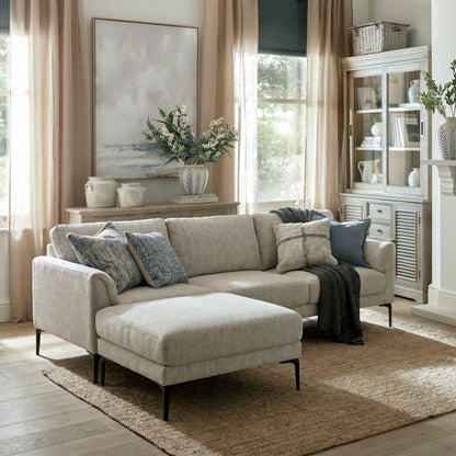 Living room with beige sectional sofa, ottoman, and decorative pillows.