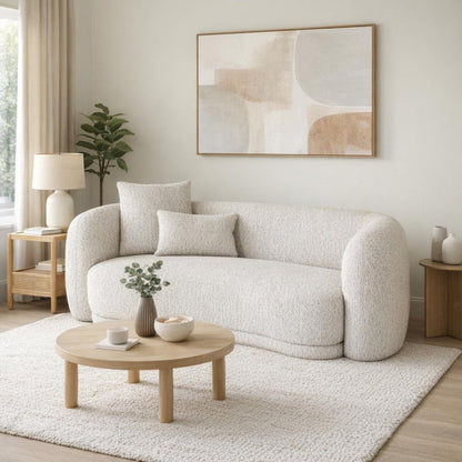 Modern living room with a light gray sofa, round wooden coffee table, and abstract art on the wall.