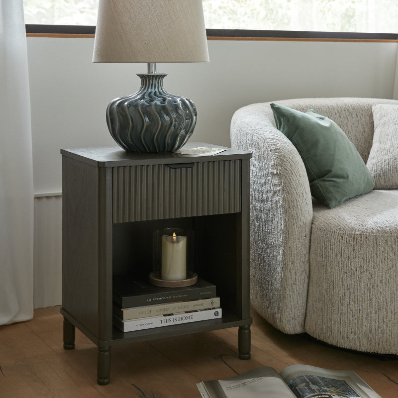 Side table with lamp and books next to a sofa in a living room