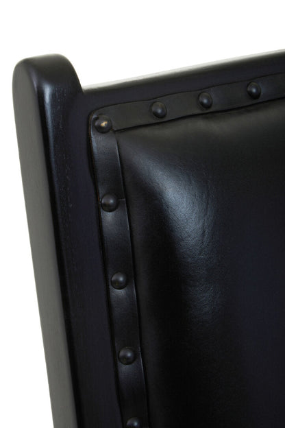 Close-up of a black leather chair with metal rivets on a white background
