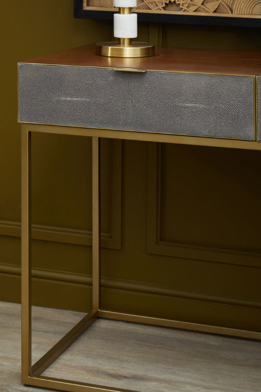 Console table with metallic frame and textured gray drawer in a room setting.