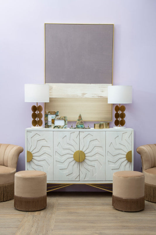 Decorative cabinet with sunburst design in a room with purple walls and beige furniture.