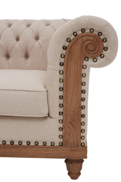Beige tufted sofa with wooden armrest and decorative nailhead trim on a white background