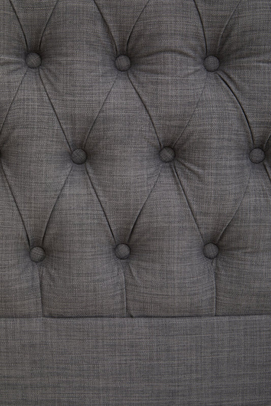Close-up of a tufted gray upholstered headboard