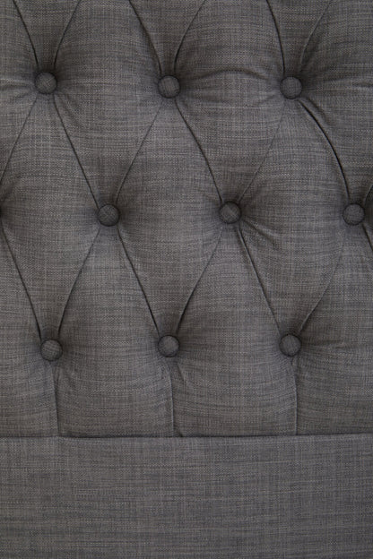 Close-up of a tufted gray upholstered headboard