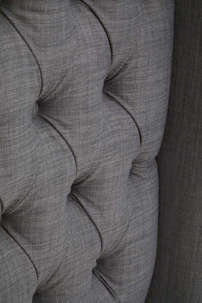 Close-up of a gray upholstered chair with tufted design