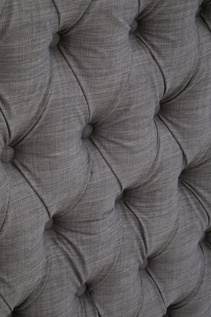 Close-up of a tufted gray fabric headboard