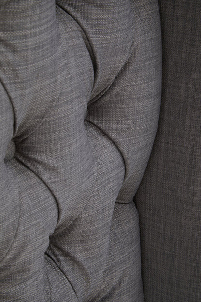 Close up of grey fabric headboard showing deep button tuff