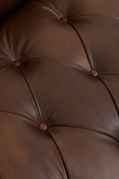 Close-up of a brown leather surface with tufted design