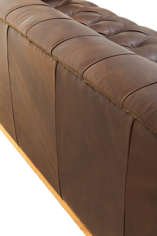 Close-up of a brown leather sofa with tufted backrest on a white background