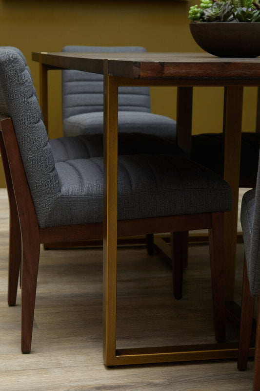 Lifestyle image of dark wooden table with brass legs with cushioned grey chairs