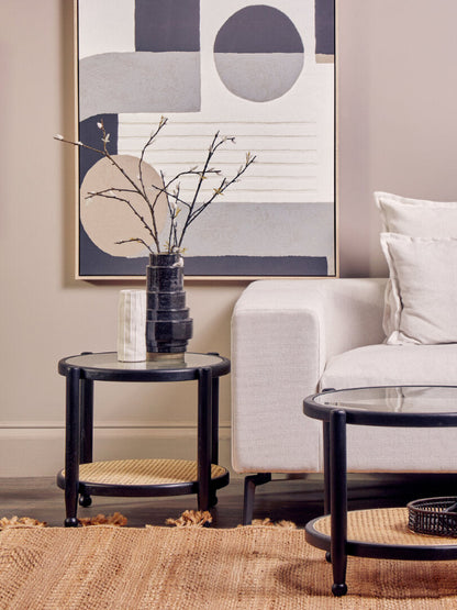 Modern living room with a white sofa, black side table, and abstract art on the wall.