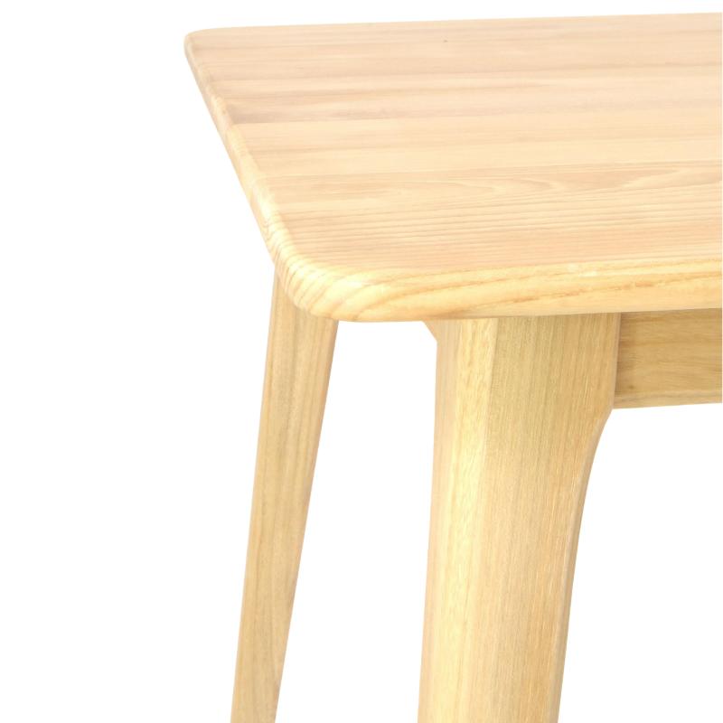Close-up of a light natural wood table corner with rounded edges and tapered legs on a white background.